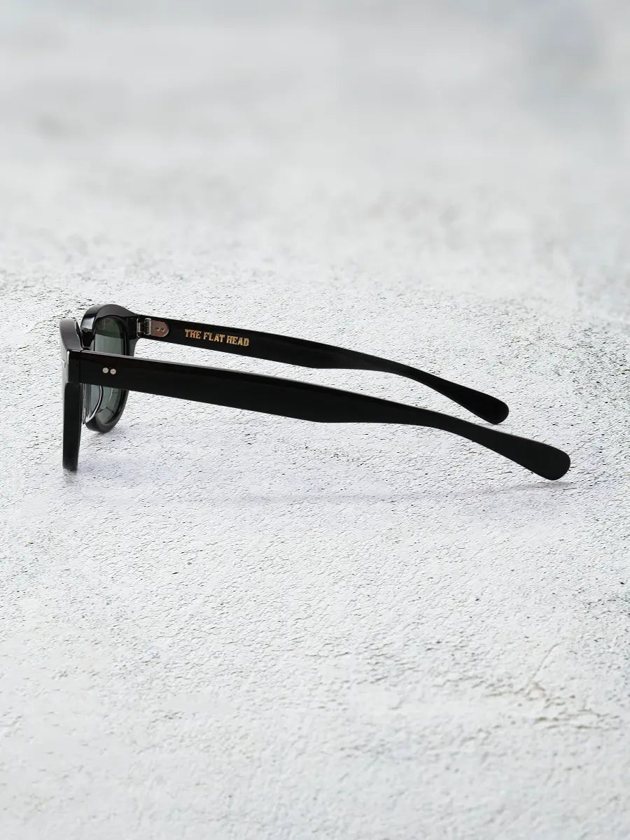 Black sunglasses with 'The Flat Gear' logo on a light gray background