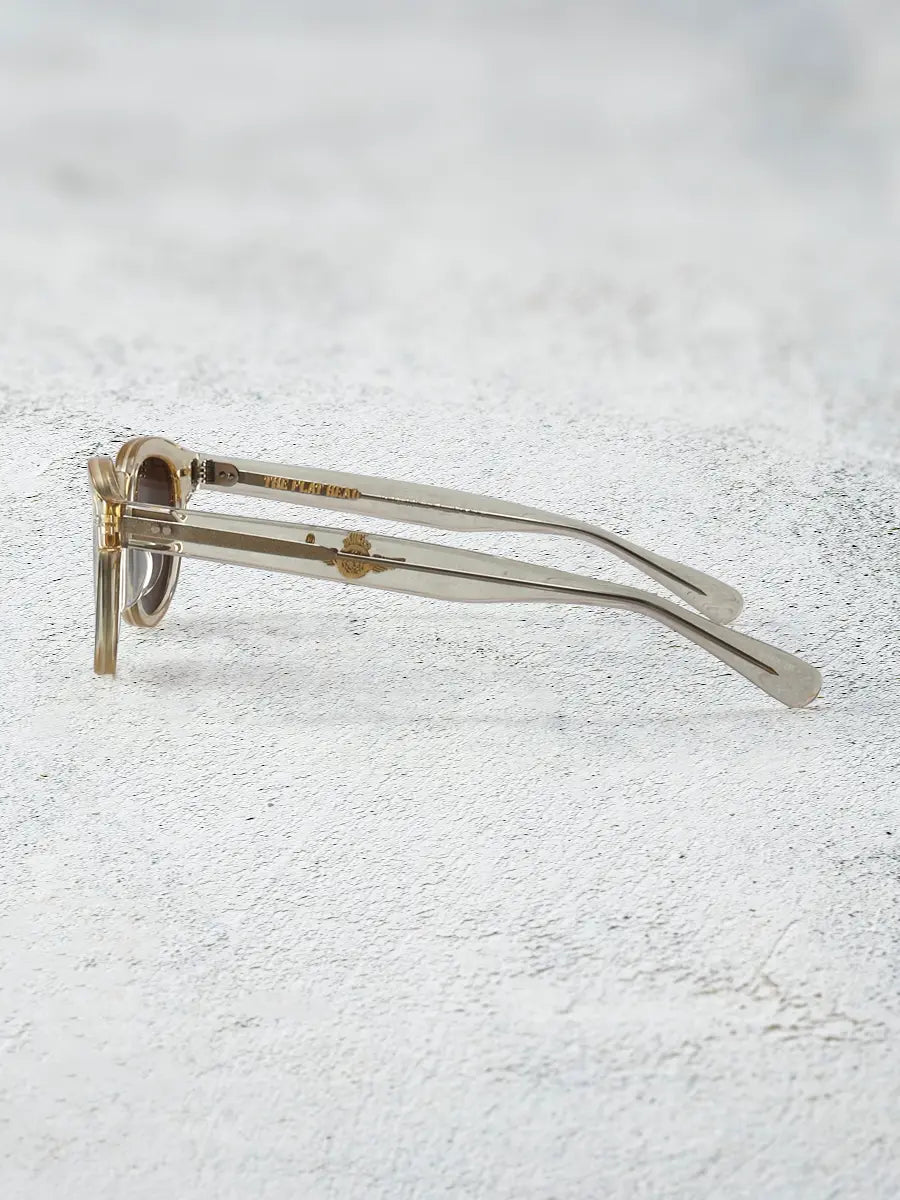 Clear eyeglasses with gold accents on a textured white surface