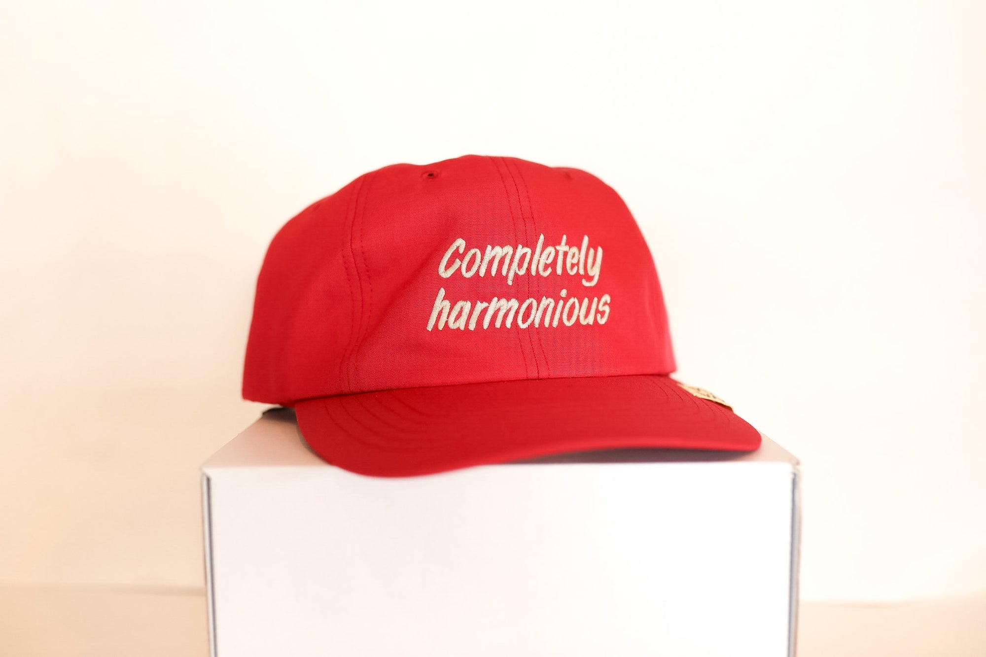 Red cap with 'Completely harmonious' text on a white box against a beige background