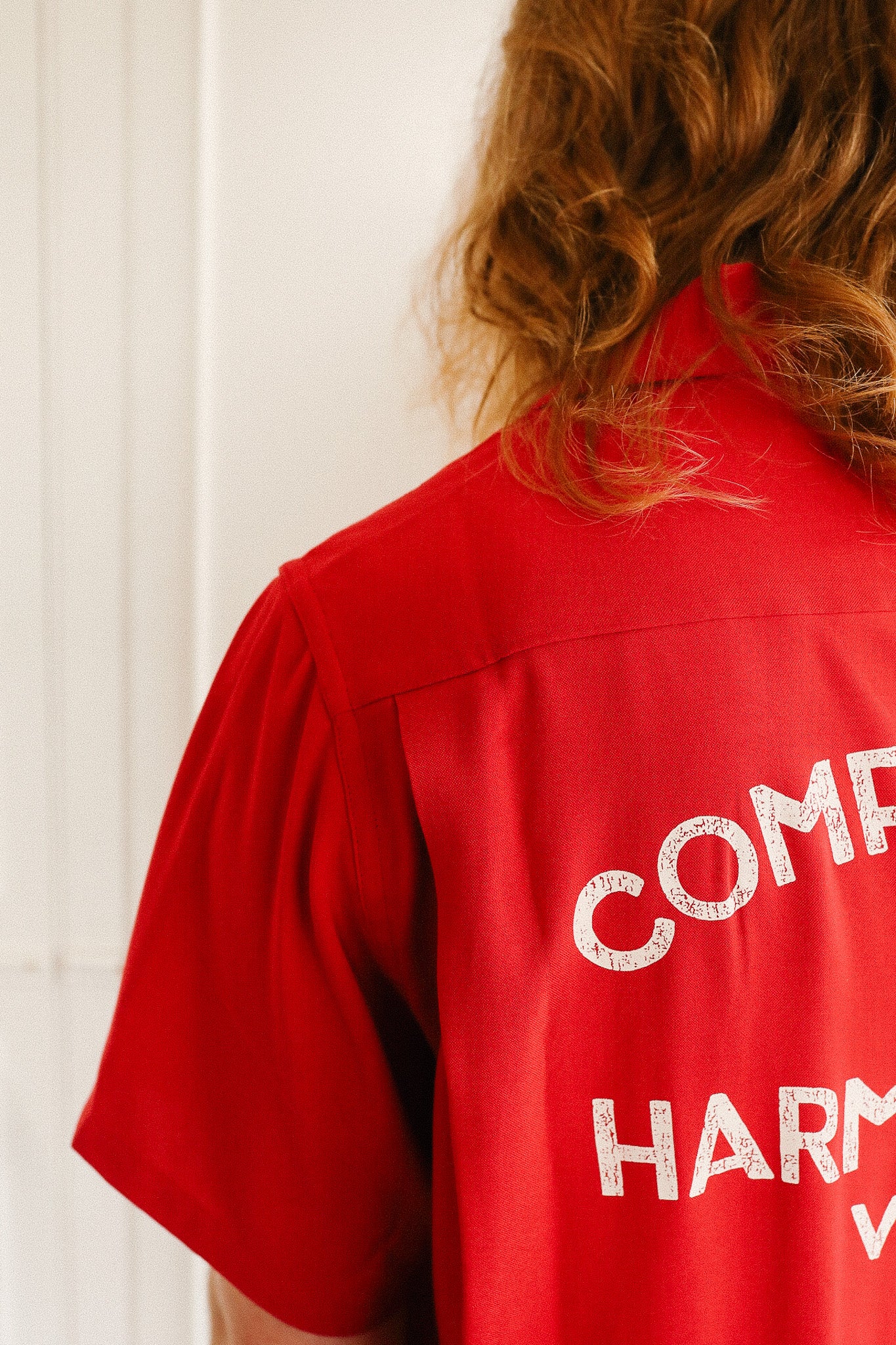 Red shirt with white text on the back, worn by a person with red hair.