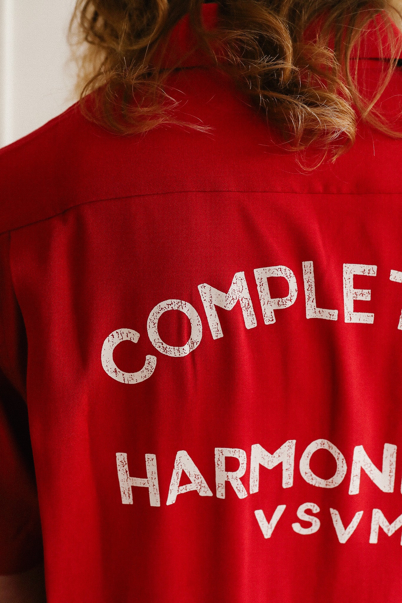 Red shirt with white text on the back, featuring the word 'COMPLETE'.