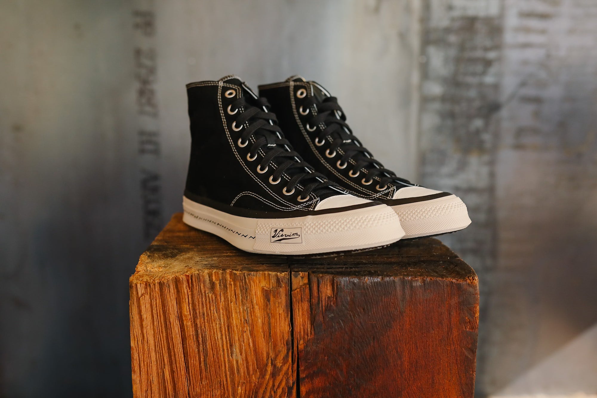 Black high-top sneakers on a wooden block with a blurred background