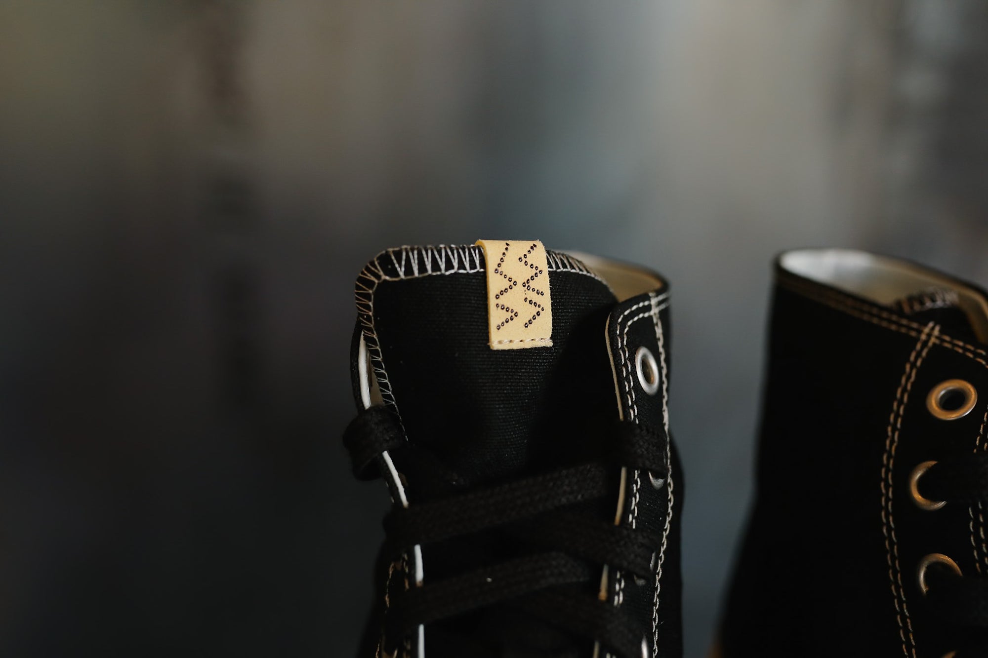 Close-up of black high-top sneakers with gold accents on a blurred background