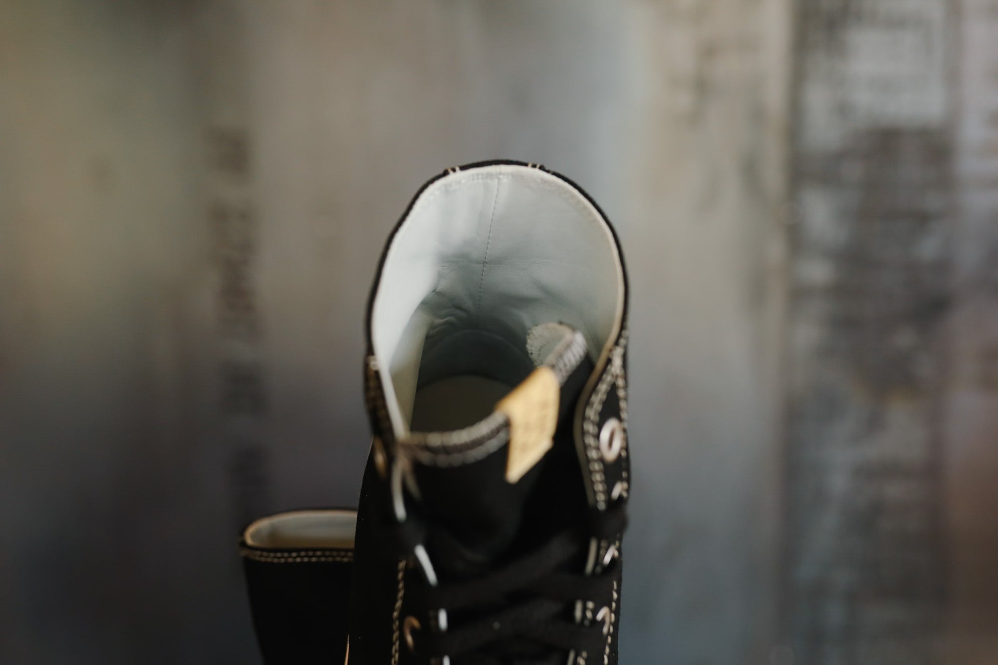 Black sneaker with white sole and decorative elements on a textured gray background