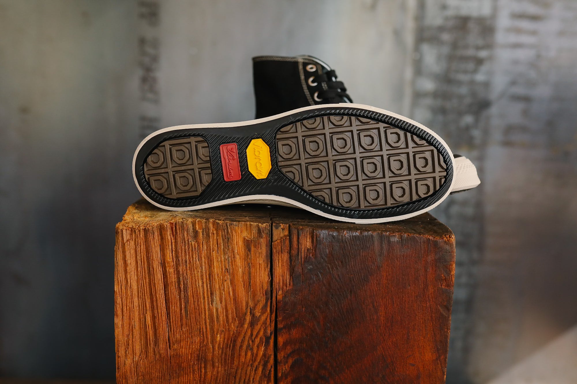Black shoe sole with a yellow label on a wooden block against a blurred background