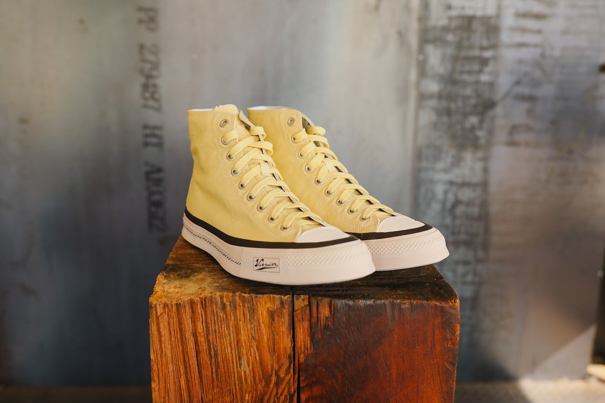 Pair of yellow high-top sneakers on a wooden block with a rustic background