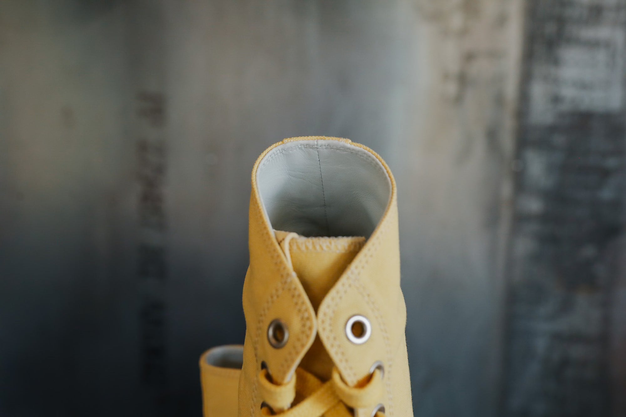 Yellow leather boot with a gray sole against a blurred background