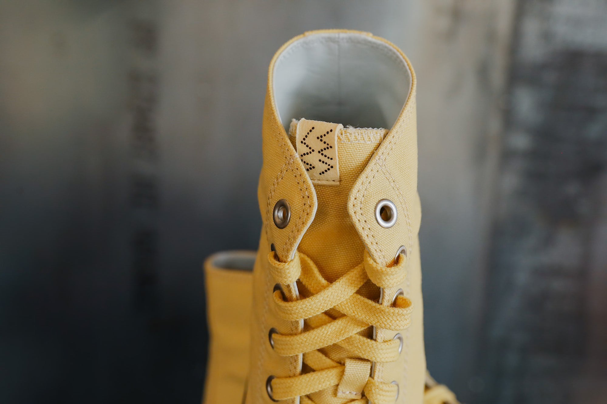 Close-up of a yellow boot with laces against a blurred background