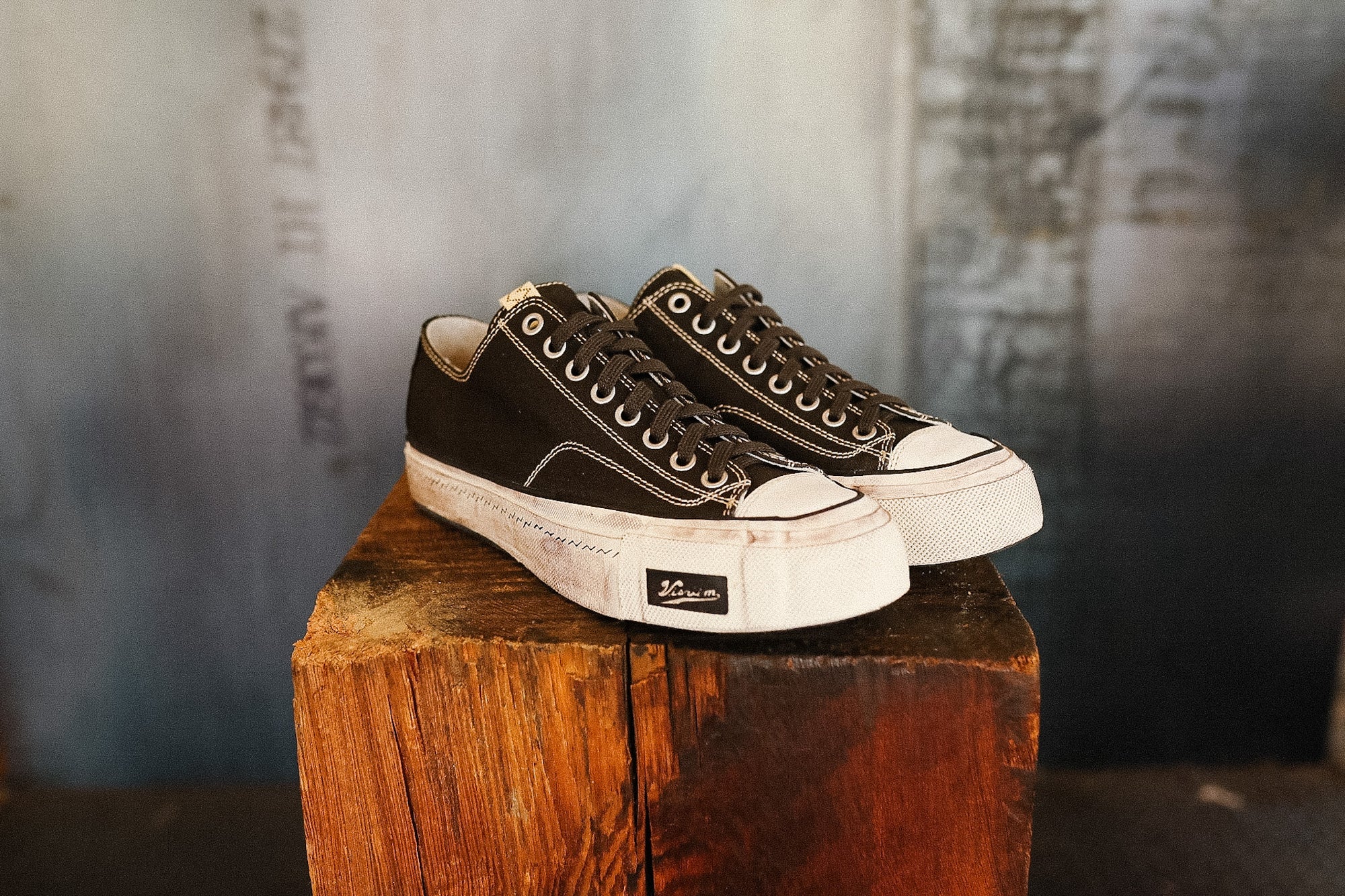 Pair of black and white sneakers on a wooden block with a blurred background