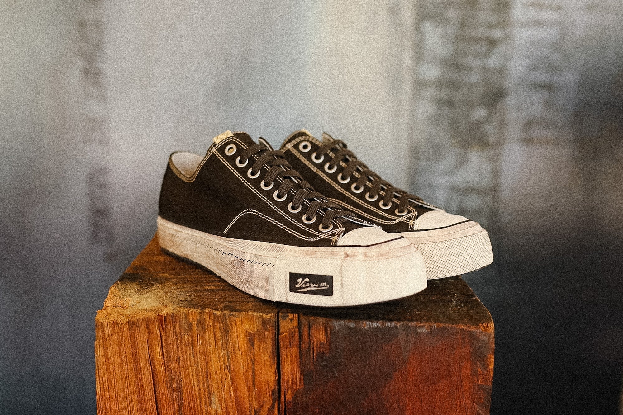 Pair of black and white sneakers on a wooden block with a blurred background