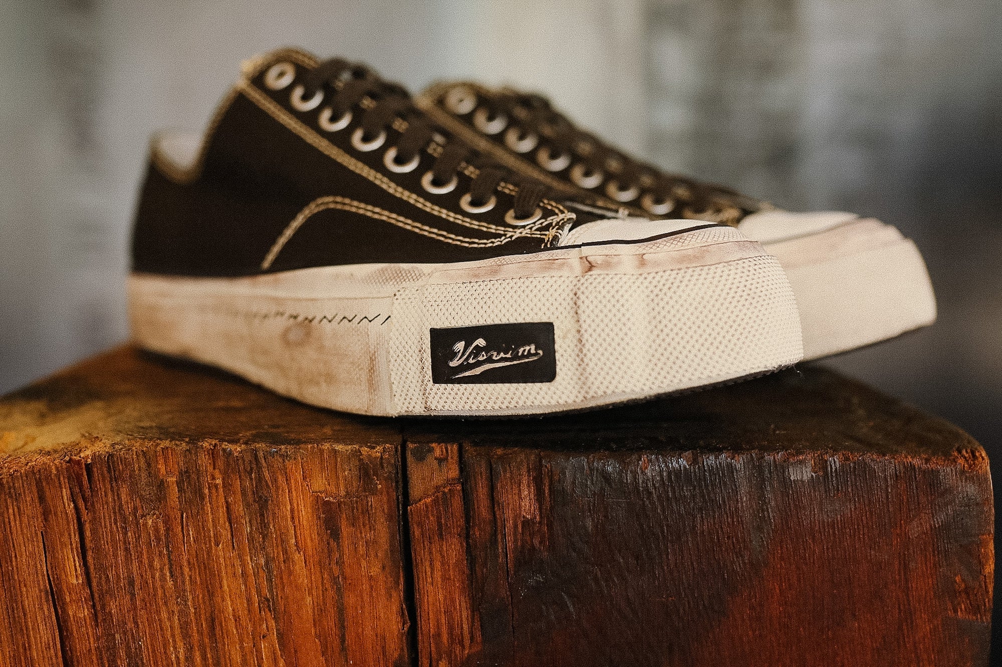 Pair of black and white sneakers on a wooden block with a blurred background
