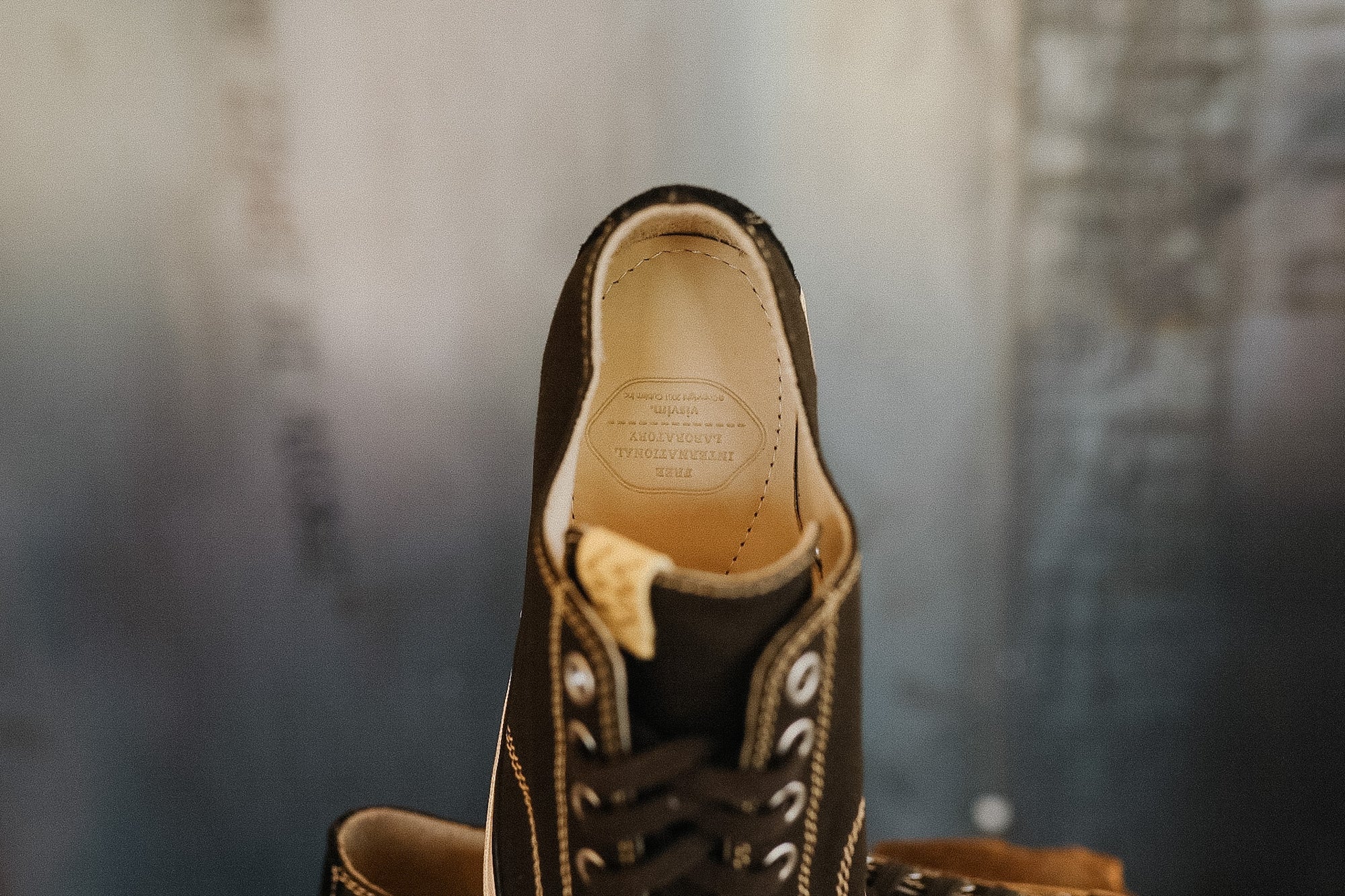 Close-up of a black leather shoe with visible stitching on a blurred background