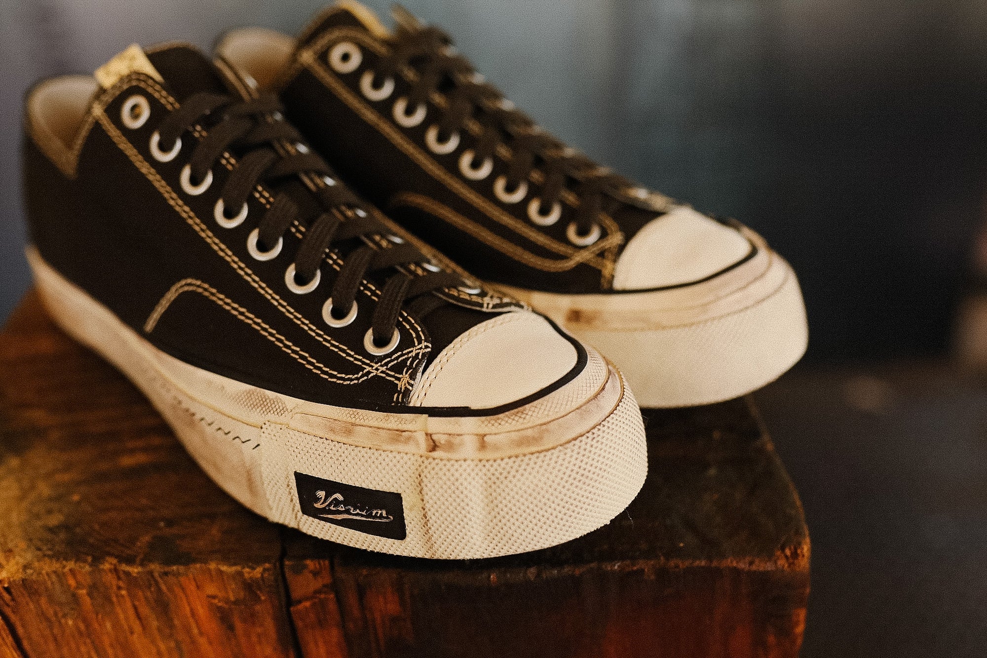 Pair of black and white sneakers on a wooden surface with a blurred background
