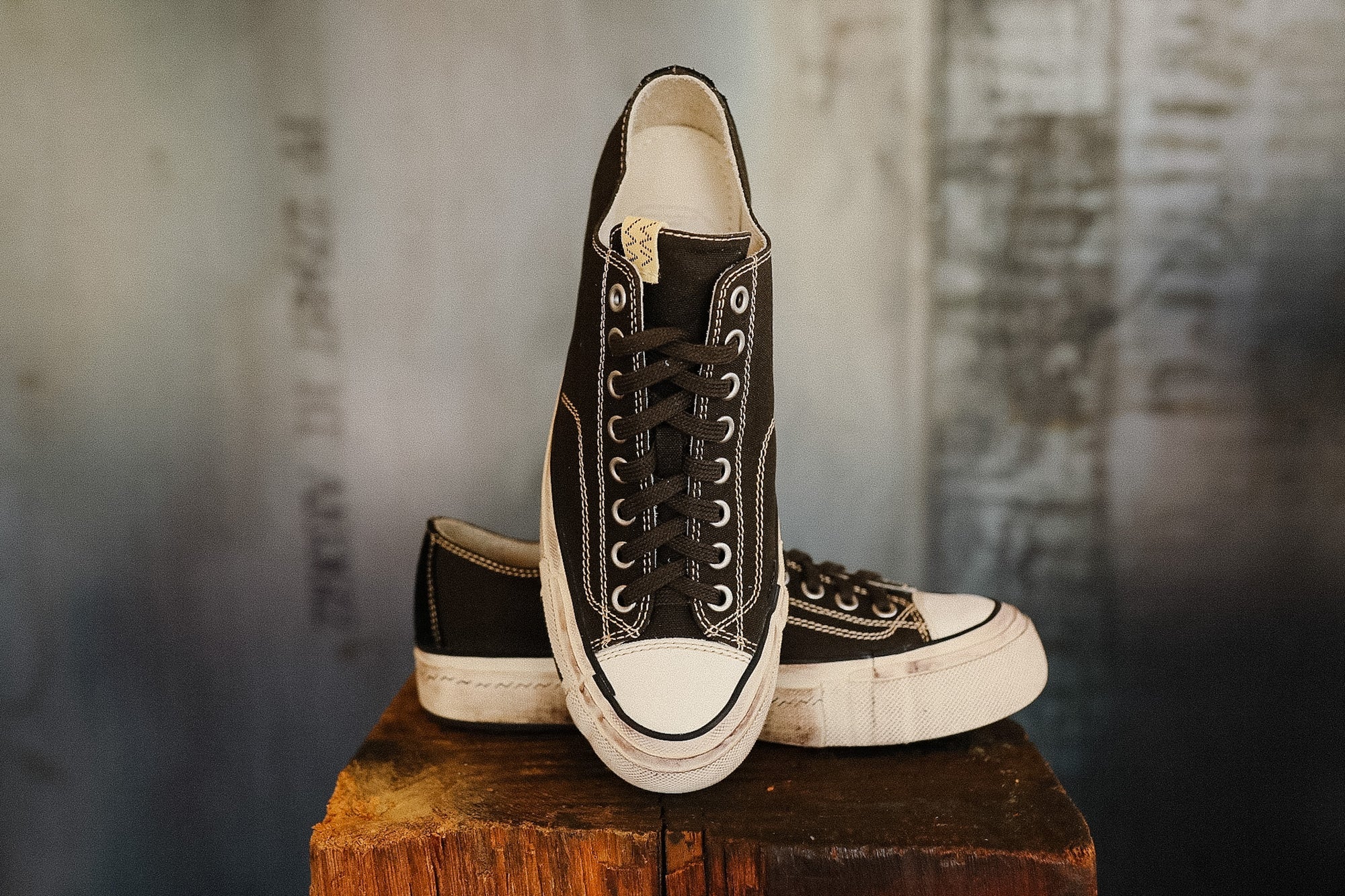 Pair of black and white sneakers on a wooden block with a textured background