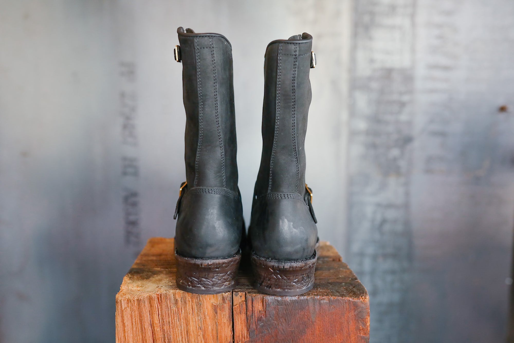 Pair of black leather boots on a wooden block with a blurred background