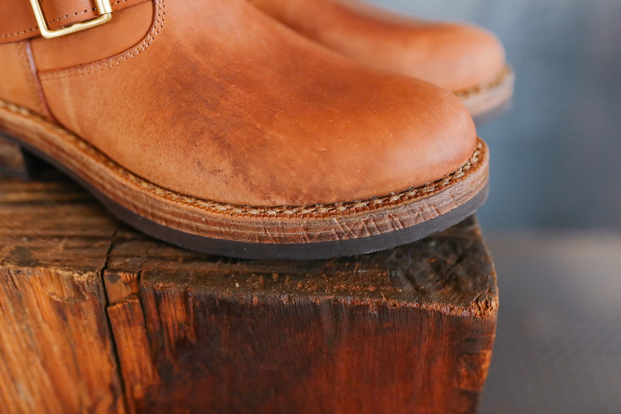 Brown leather boots on a wooden block with a blurred background