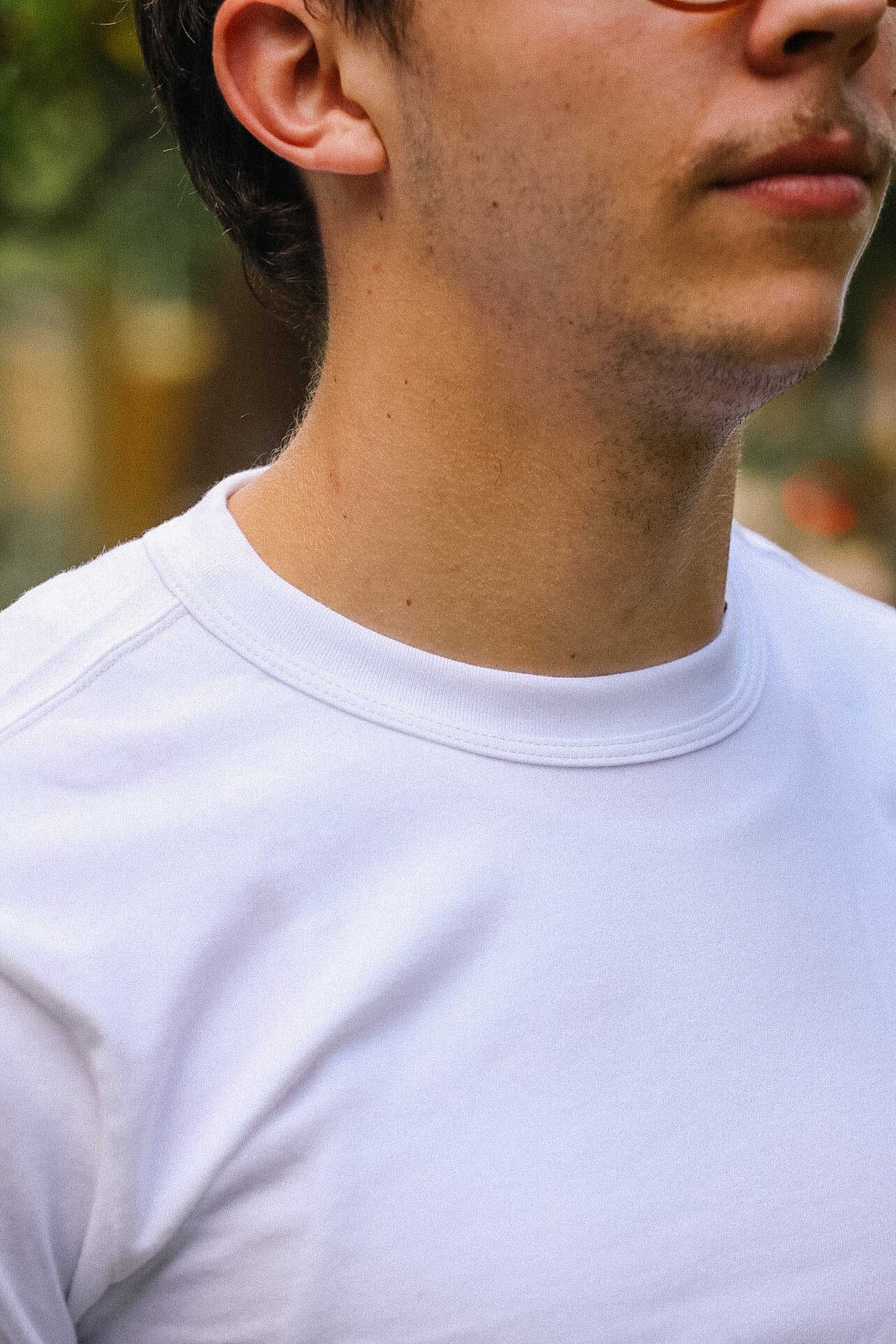 Close-up of a person wearing a white t-shirt with a blurred background