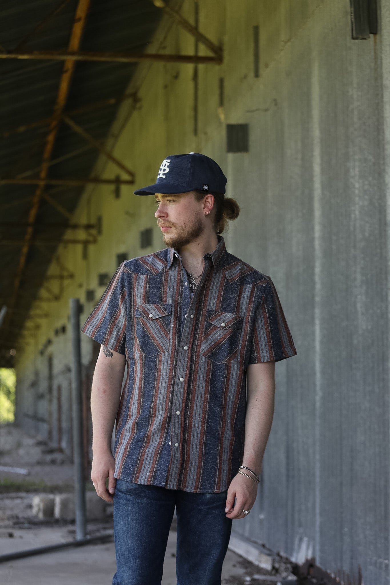 man wearing a stripe shirt standing in an industrial setting 