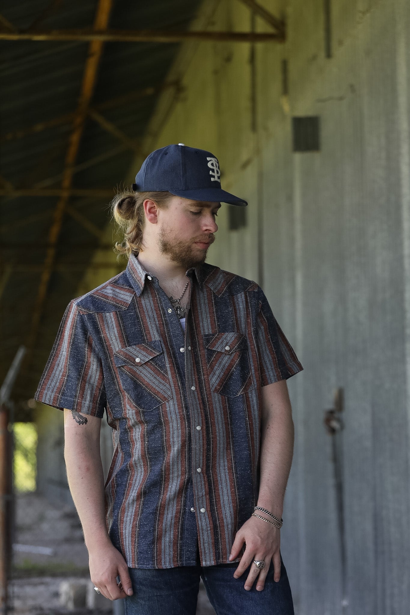 man wearing a stripe shirt standing in an industrial setting 