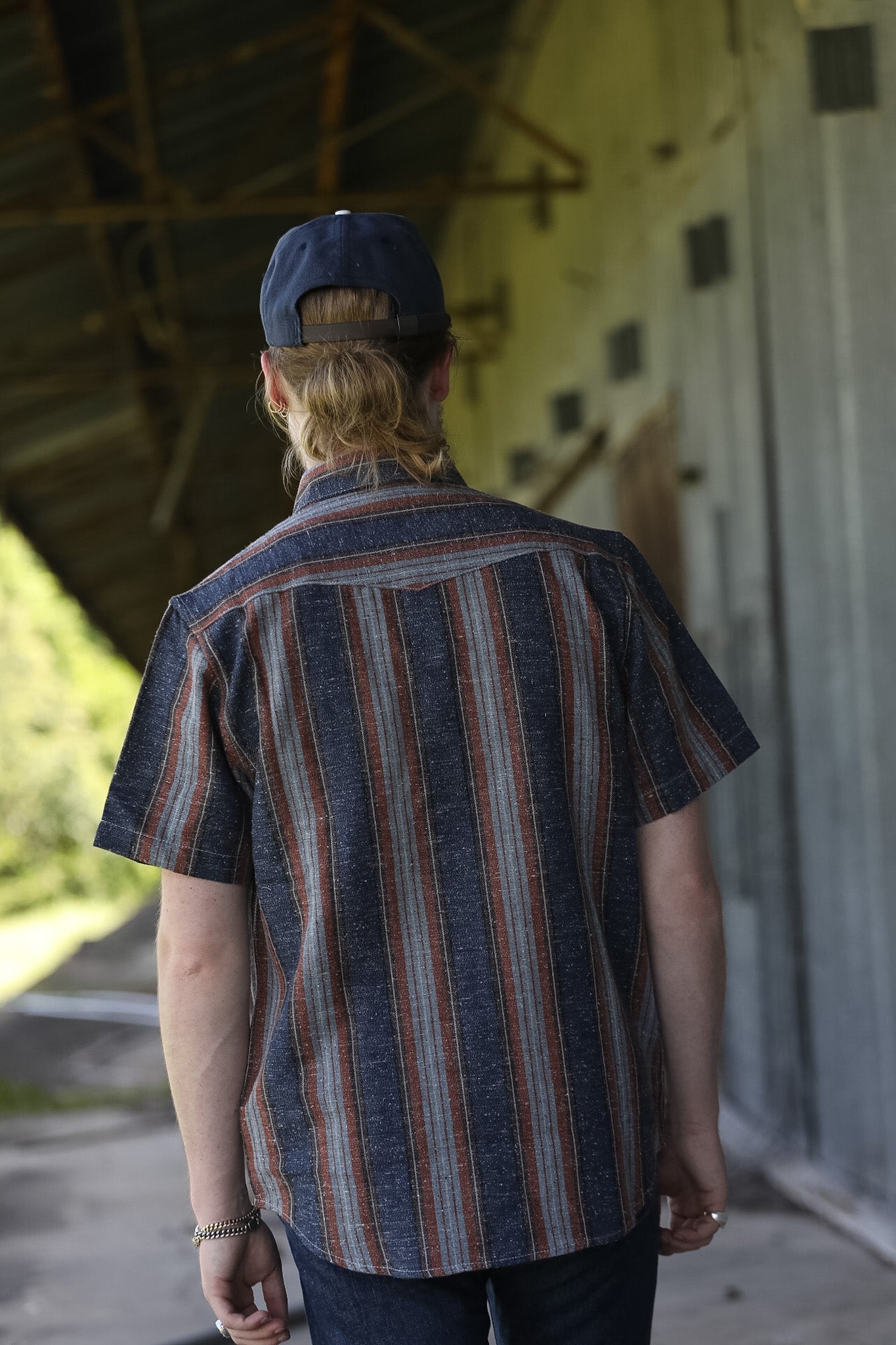 man wearing a stripe shirt standing in an industrial setting 