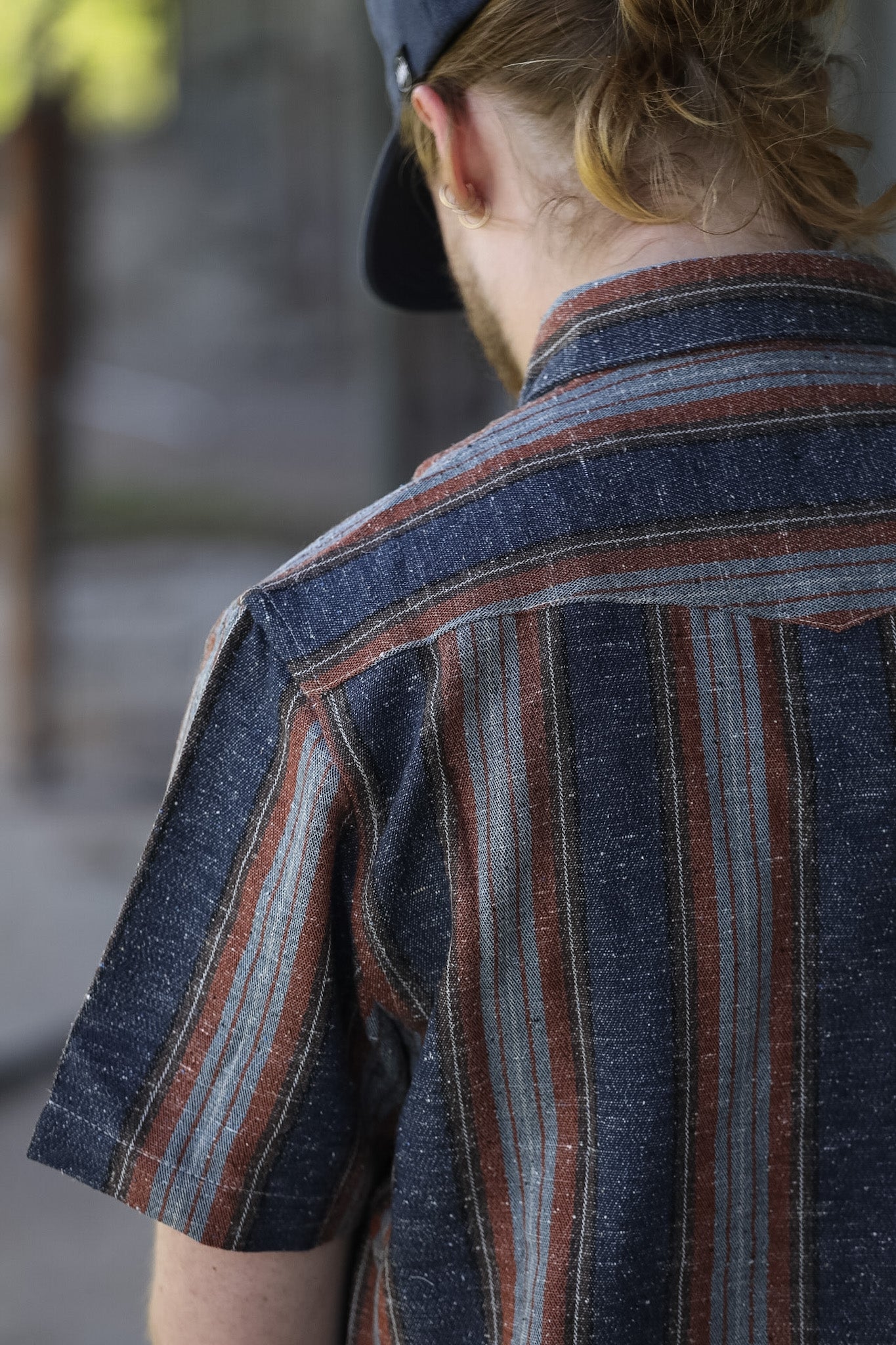 man wearing a stripe shirt standing in an industrial setting 