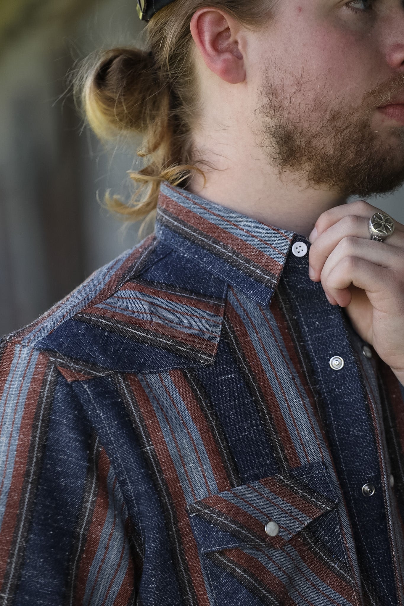 man wearing a stripe shirt standing in an industrial setting 