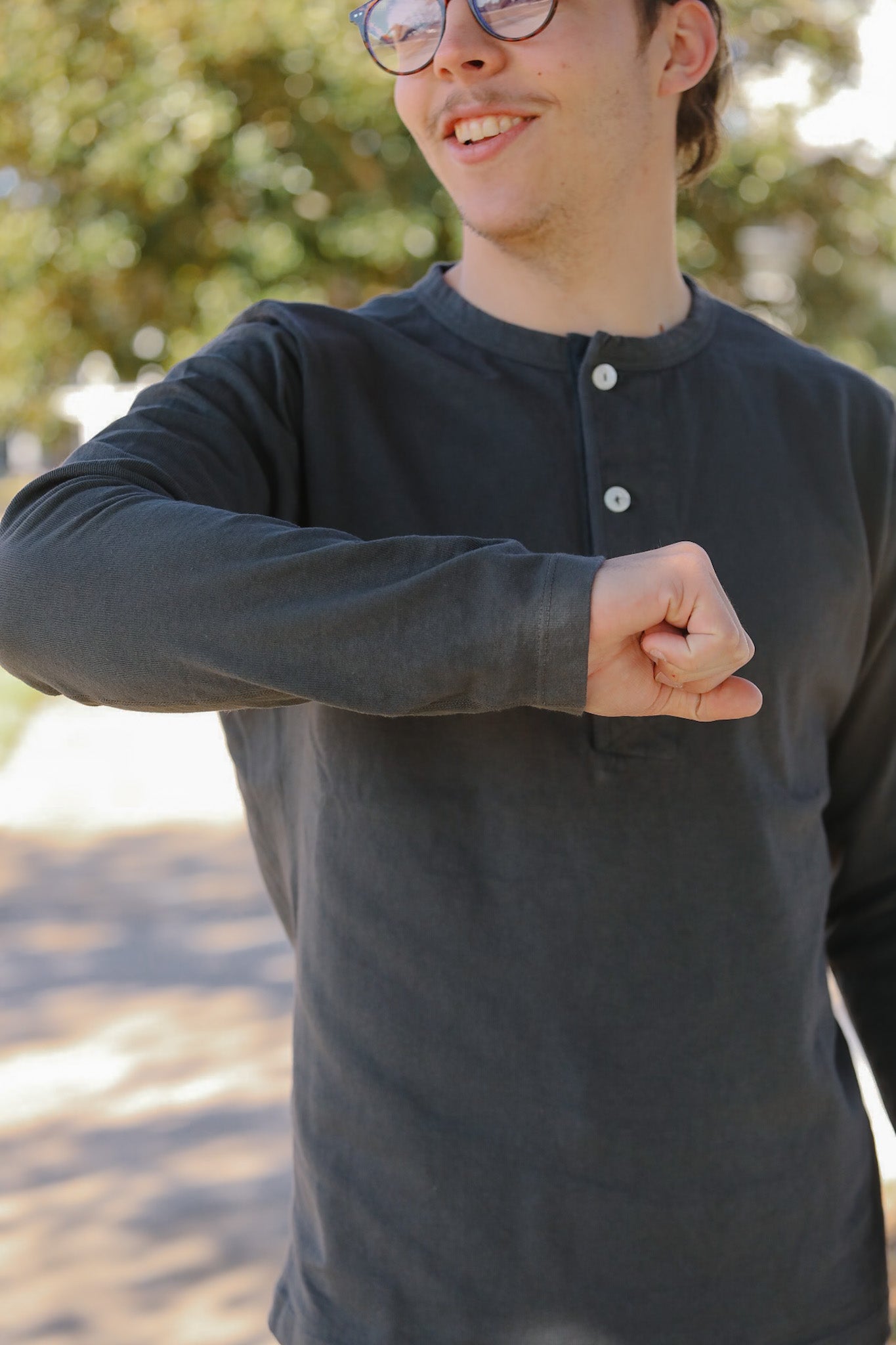 Person wearing a black long-sleeve shirt with buttons outdoors