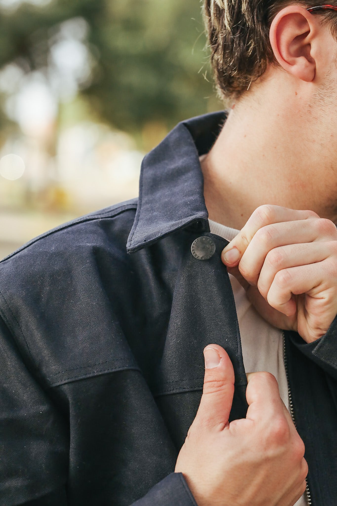 Person adjusting the collar of a dark jacket outdoors