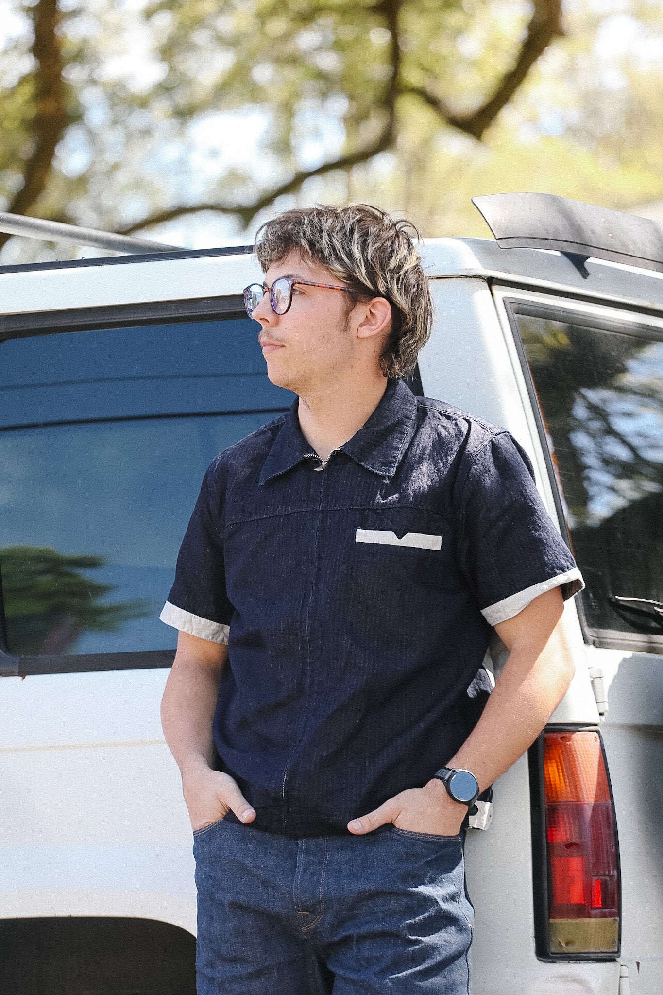 Person standing next to a white vehicle with trees in the background